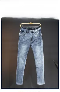 Detail of slim fit light blue washed denim pants featuring vintage faded effect and metal button