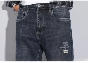 Detail of dark blue stretch denim jeans featuring intricate embroidery and washed texture