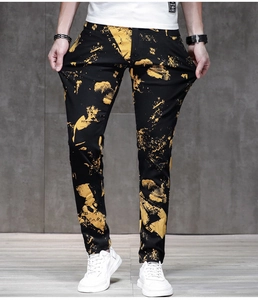 Dettaglio dei jeans neri slim fit con schizzi di vernice gialla e stampa di lettere