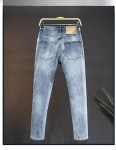 Detail view of the back of slim-fit light blue washed jeans with leather waist tag