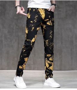 Dettaglio dei jeans neri slim da uomo con stampa graffiti gialla e schizzi di vernice