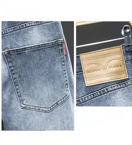 Detail of premium light blue washed jeans with leather brand tag and stitched back pocket
