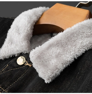 Close-up of a black denim jacket collar with thick grey faux shearling and gold button