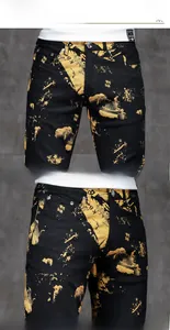 Dettaglio dei pantaloni in denim nero slim fit con stampa dorata e bottone metallico