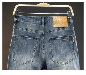 Detailed macro view of washed dark blue denim waist with leather tag and classic embroidery