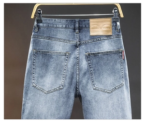 Detail of light blue washed denim jeans showing back pockets and brown leather brand patch