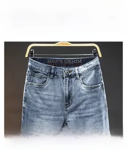 Detail of blue wash denim waist showing metal button, zipper fly and inner logo print