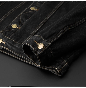 Close-up of black denim jacket with contrast stitching and golden embossed jeans button