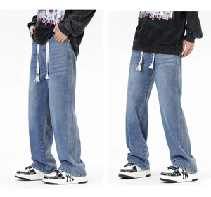 Détail du jean large bleu clair avec cordon de serrage crème réglable et logo X brodé