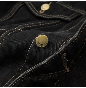 Detail of vintage brass buttons and contrast stitching on black denim jacket