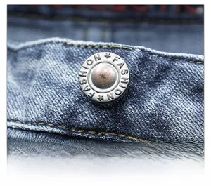 Macro detail of high-quality denim waistband with vintage metal button and orange stitching
