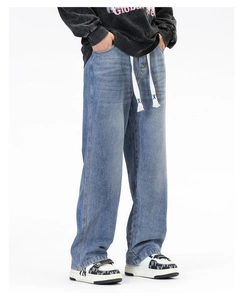 Détail du jean en denim bleu clair à jambes larges avec taille à cordon blanc unique