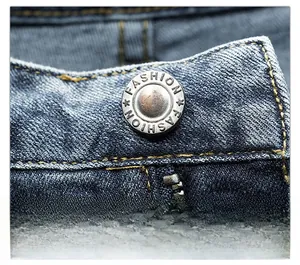 Detailed macro view of deep blue denim jeans waist with vintage metal button and stitching