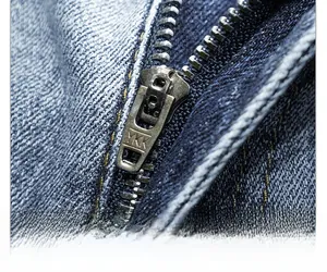 Close-up of high-quality YKK metal zipper on dark blue slim fit denim jeans pants