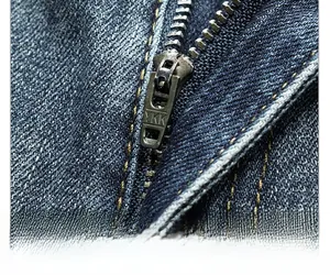 Close-up of premium YKK metal zipper and high-quality stitching on dark blue denim jeans