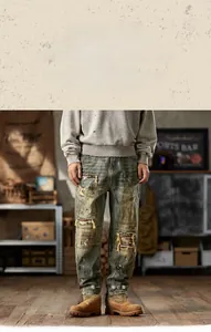 Close-up of vintage blue jeans featuring distressed rips, patches, and paint splatter details