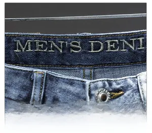 Macro view of men's slim denim jeans waist with detailed embroidery and metal button