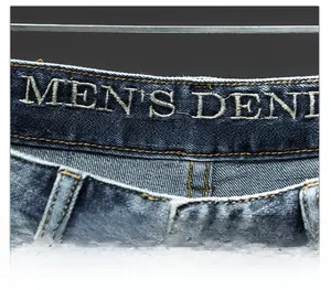 Detailed close-up of premium dark blue denim jeans featuring intricate waist embroidery