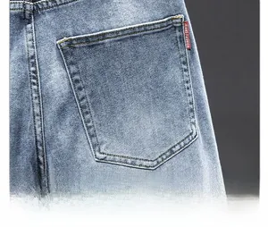Close-up of light blue denim jeans rear pocket with red woven label and detailed stitching