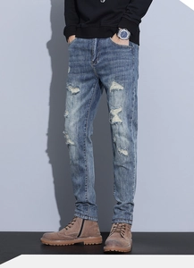 Detail of vintage distressed denim texture with ripped holes and whiskers on slim fit jeans