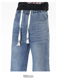 Détail du jean denim bleu délavé avec taille élastique et cordons de serrage blancs