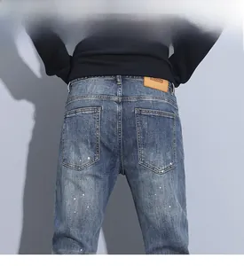 Detailed back view of blue slim fit distressed jeans featuring white paint splatter and leather patch