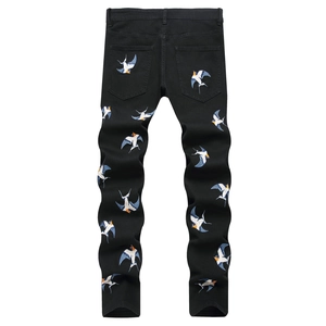 Men's slim fit black denim pants featuring colorful swallow embroidery on the back