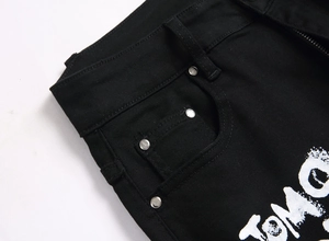 Detailed macro view of black stretch jeans with white Tomorrow print and silver metal rivets