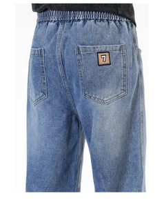 Détail de l'arrière du jean avec taille élastique et broderie du chiffre sept sur la poche