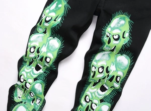 Détail de l'imprimé crâne vert fluo sur un jean noir punk gothique et hip hop