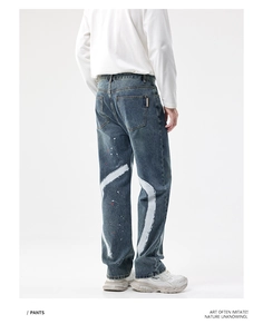 Détail d'un jean droit ample avec traits blancs peints à la main et taches de peinture rouge