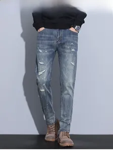 Detailed close-up of distressed blue slim fit jeans with paint splatters and ripped texture