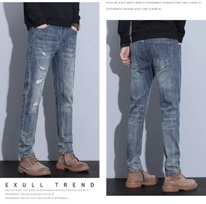 Detail of slim fit light blue distressed jeans with ripped knees and white paint splatters