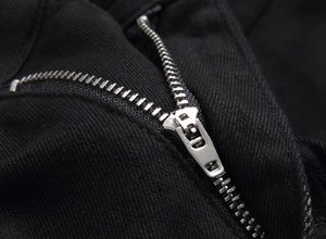 Detailed close-up of high-quality silver metal zipper and black denim fabric texture