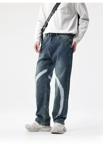 Détail d'un jean bleu délavé pour homme avec traces de peinture blanche et taches d'encre