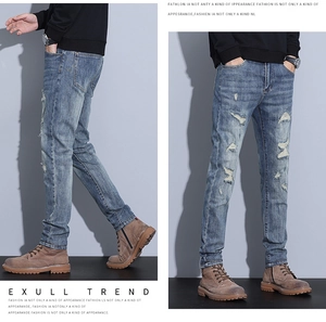 Detail view of slim fit light blue ripped jeans with vintage washed whiskers and distressed finish