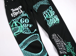 Detail of black slim denim jeans with white and mint green street graffiti print patterns