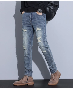 Close-up detail of distressed ripped effects on mid-blue straight slim fit denim jeans
