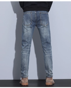 Detail view of men's slim fit jeans with unique white ink splash and back pocket design