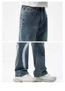 Détail du jean bleu style urbain avec des effets d'éclaboussures de peinture blanc et rouge