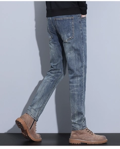 Detail view of slim fit blue men's jeans with white paint splatter and classic five-pocket design