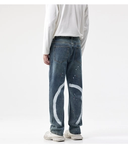 Détail arrière d'un jean bleu délavé avec motif de peinture blanche et éclaboussures rouges
