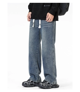 Détail de jean large droit avec cordon blanc et texture denim délavée de style vintage