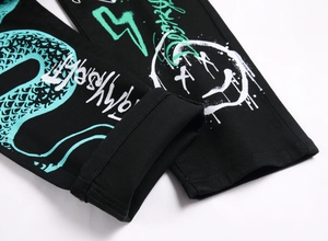 Detailed close-up of street graffiti prints and cuffed hem on black slim stretch jeans