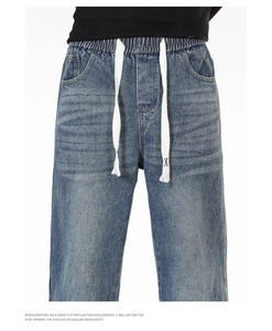 Détail du jean bleu délavé avec taille élastique et cordon de serrage blanc brodé