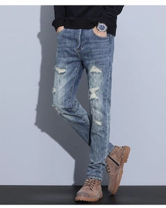 Detail of distressed light blue denim jeans with vintage ripped knees and whiskered texture