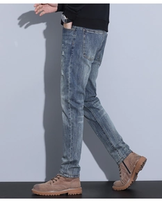 Detail view of slim fit light blue jeans showing whiskering and white paint splatter effects
