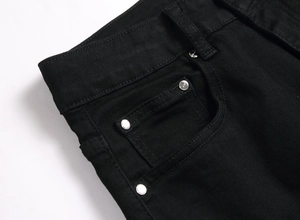 Détail d'un jean gothique noir avec rivets en métal argenté et poche à monnaie