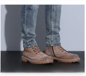 Detail showing blue washed denim pants hem paired with brown lace-up boots and rubber sole