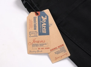 Close-up of vintage brown paper tags on slim-fit black denim fabric with high-quality texture